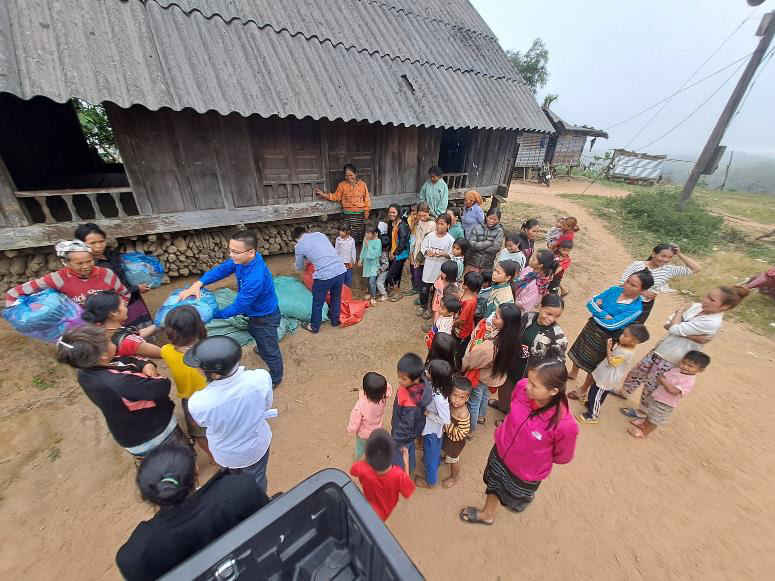 Mr Ha handing out the clothes packs, with Mr Khoa (a Commune leader) leaning over opening the orange bag